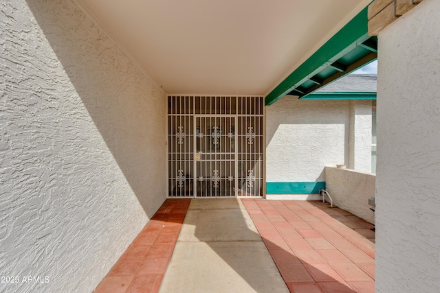 view of exterior entry with a balcony and stucco siding