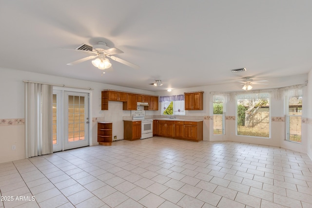 kitchen with light countertops, brown cabinetry, a ceiling fan, and white range with electric cooktop