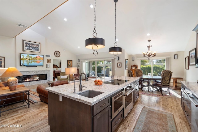 kitchen featuring open floor plan, black electric stovetop, a sink, and decorative light fixtures