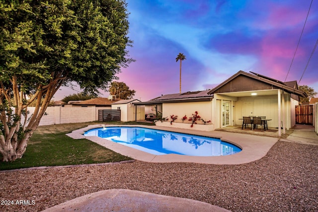 pool at dusk featuring a patio and a shed