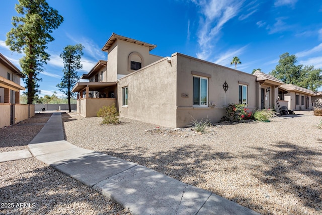 view of side of home with fence and stucco siding