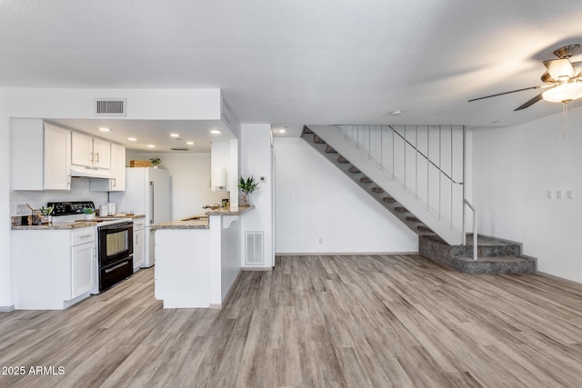 kitchen with white cabinets, range with electric stovetop, visible vents, and a peninsula