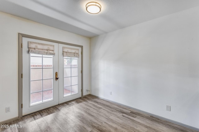 empty room with a wealth of natural light, french doors, and light wood-style flooring