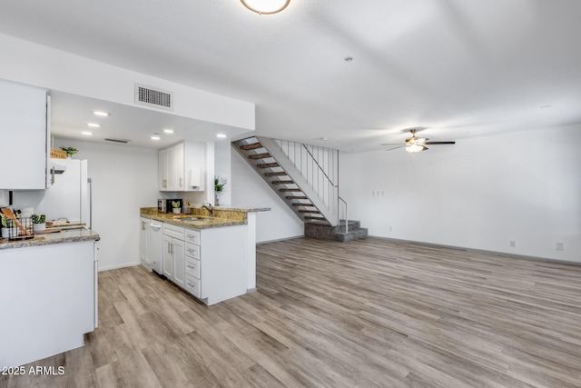 kitchen featuring visible vents, light stone counters, a sink, and white cabinetry