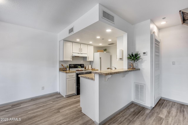 kitchen featuring visible vents, freestanding refrigerator, white cabinets, range with electric cooktop, and under cabinet range hood