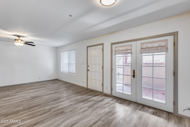 interior space with light wood-style floors, french doors, baseboards, and a ceiling fan