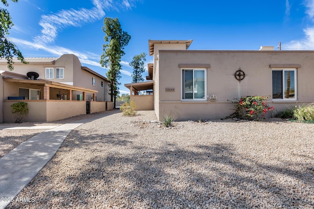 view of front facade with fence and stucco siding