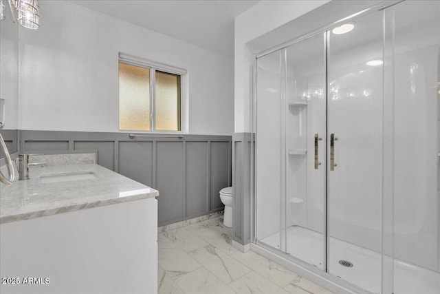 bathroom featuring vanity, toilet, and a shower with shower door