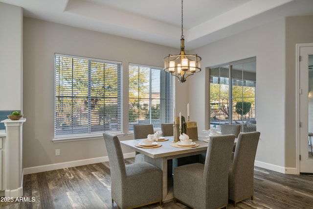 dining space with an inviting chandelier, a raised ceiling, and plenty of natural light