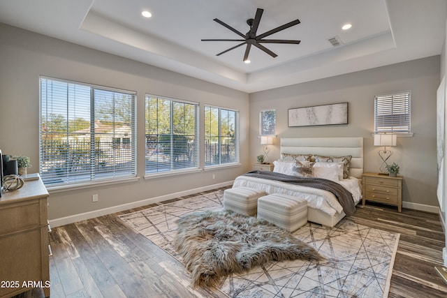 bedroom featuring wood-type flooring, a tray ceiling, and ceiling fan