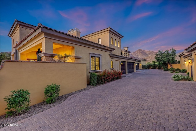 18927 N 101st St, Scottsdale, AZ 85255 - property exterior at dusk with decorative driveway, a chimney, fence, and stucco siding