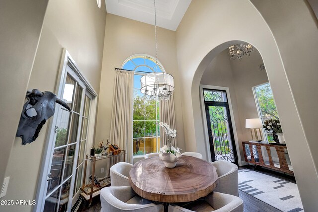 18927 N 101st St, Scottsdale, AZ 85255 - dining area featuring a chandelier, a high ceiling, arched walkways, and wood finished floors