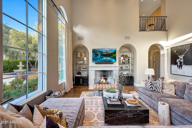 18927 N 101st St, Scottsdale, AZ 85255 - living area featuring a towering ceiling, a high end fireplace, wood finished floors, arched walkways, and baseboards