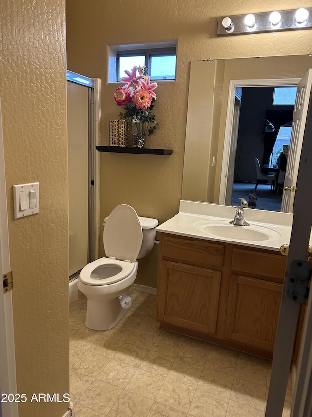 bathroom with toilet, a shower with door, and vanity