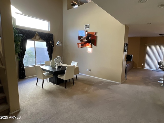 carpeted dining room featuring a high ceiling