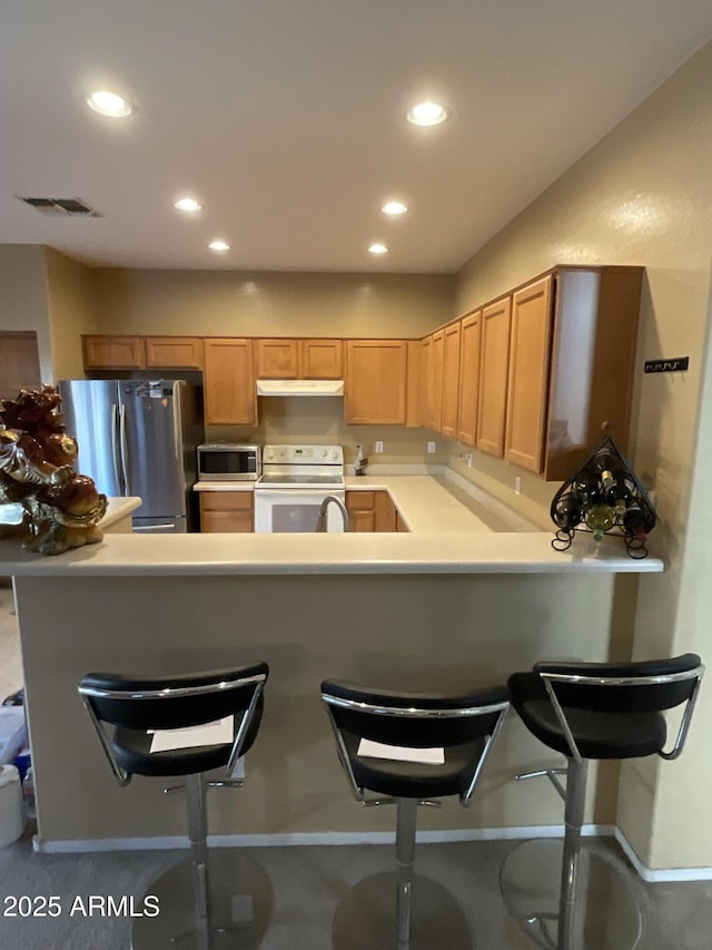 kitchen featuring stainless steel appliances, a kitchen bar, and kitchen peninsula