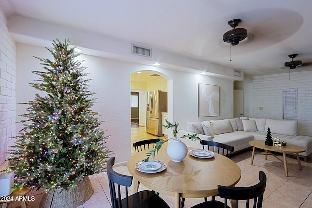 dining area featuring ceiling fan, light tile patterned floors, and brick wall