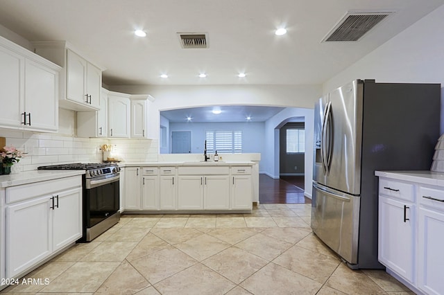 kitchen featuring white cabinets, sink, light tile patterned floors, appliances with stainless steel finishes, and kitchen peninsula