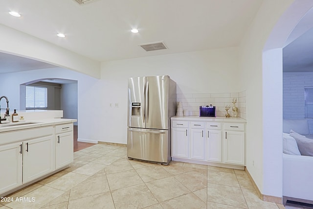 kitchen featuring stainless steel fridge with ice dispenser, light tile patterned floors, white cabinetry, and sink