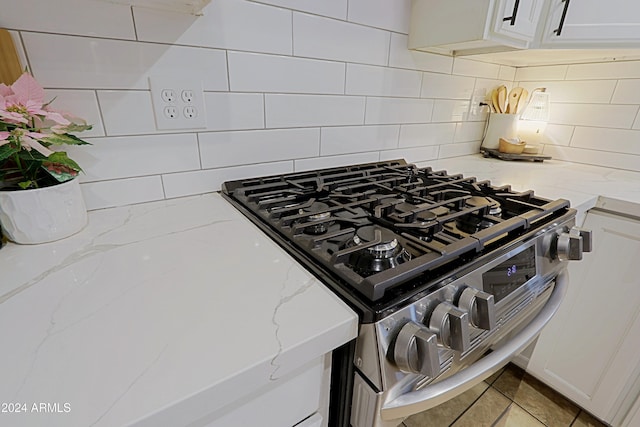 details with gas stove, white cabinetry, and light stone counters