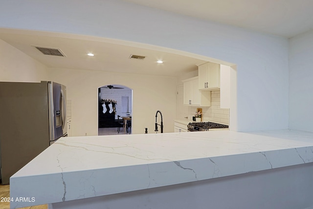 kitchen with tasteful backsplash, kitchen peninsula, white cabinetry, and appliances with stainless steel finishes