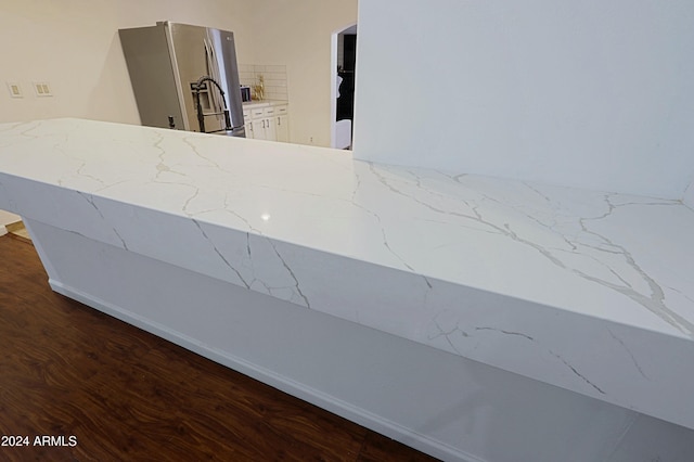 room details featuring light stone counters, stainless steel fridge with ice dispenser, and dark wood-type flooring