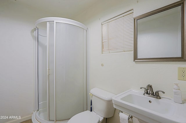 bathroom featuring toilet, a shower with shower door, and sink