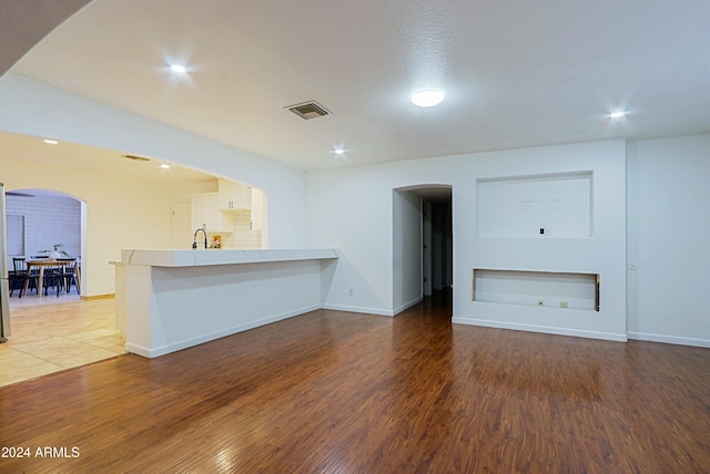 unfurnished living room with sink and dark wood-type flooring