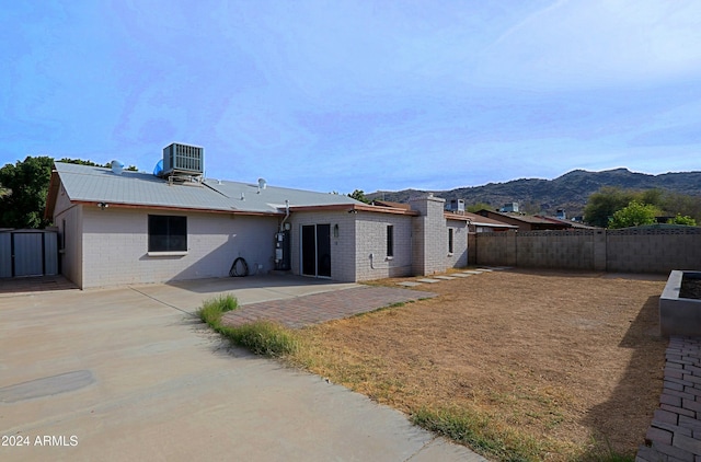 rear view of property with a mountain view, gas water heater, central AC, and a patio area