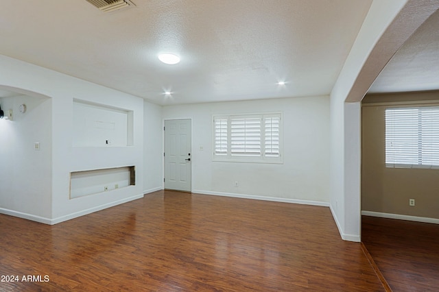 unfurnished living room with dark hardwood / wood-style floors and a textured ceiling