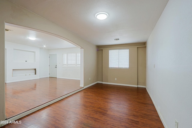 empty room with dark hardwood / wood-style flooring, a healthy amount of sunlight, and a textured ceiling