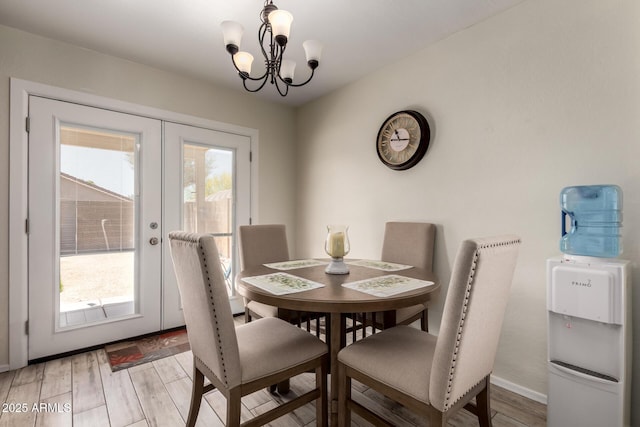 dining room featuring an inviting chandelier, light wood-style flooring, baseboards, and french doors