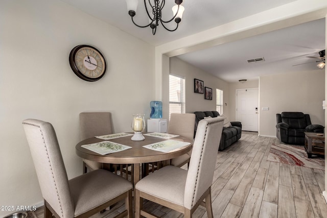 dining room featuring visible vents, light wood-style flooring, ceiling fan with notable chandelier, and baseboards
