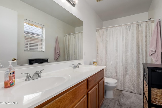 bathroom with a sink, toilet, double vanity, and visible vents