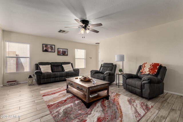 living area featuring ceiling fan, visible vents, baseboards, and light wood finished floors
