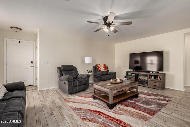 living area featuring baseboards, a ceiling fan, and wood finished floors