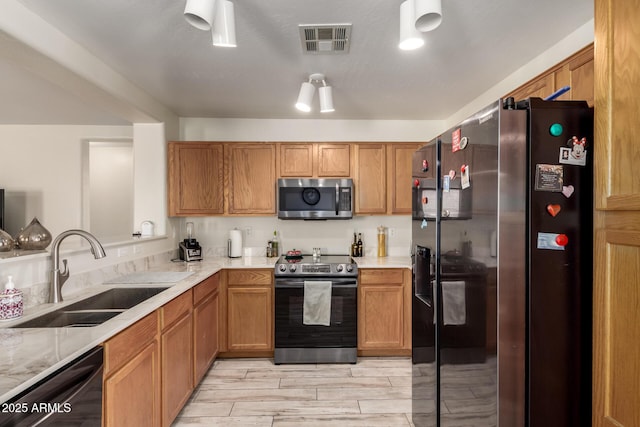 kitchen featuring visible vents, a sink, brown cabinets, and stainless steel appliances
