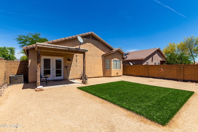 rear view of house with a fenced backyard, a patio area, stucco siding, and french doors