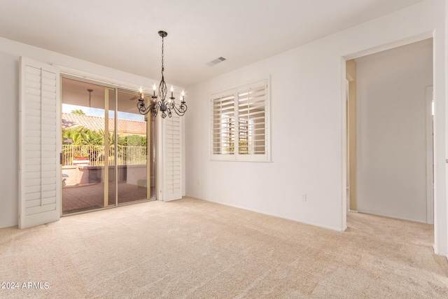 spare room with light colored carpet and a notable chandelier