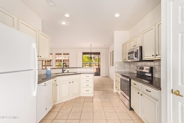 kitchen featuring sink, stainless steel appliances, kitchen peninsula, pendant lighting, and light tile patterned flooring