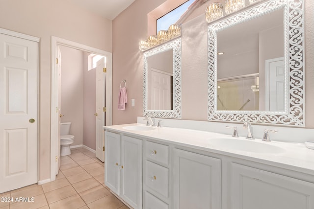 bathroom featuring tile patterned floors, a shower with door, vanity, and toilet