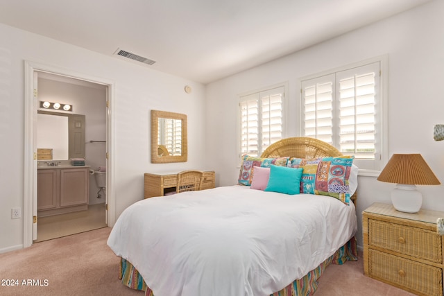 carpeted bedroom with ensuite bathroom and multiple windows