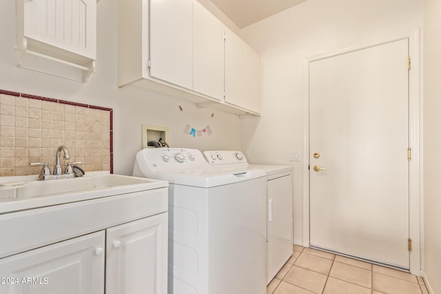 laundry room with sink, light tile patterned floors, cabinets, and independent washer and dryer