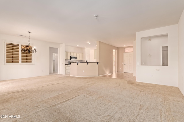 unfurnished living room with a notable chandelier and light carpet