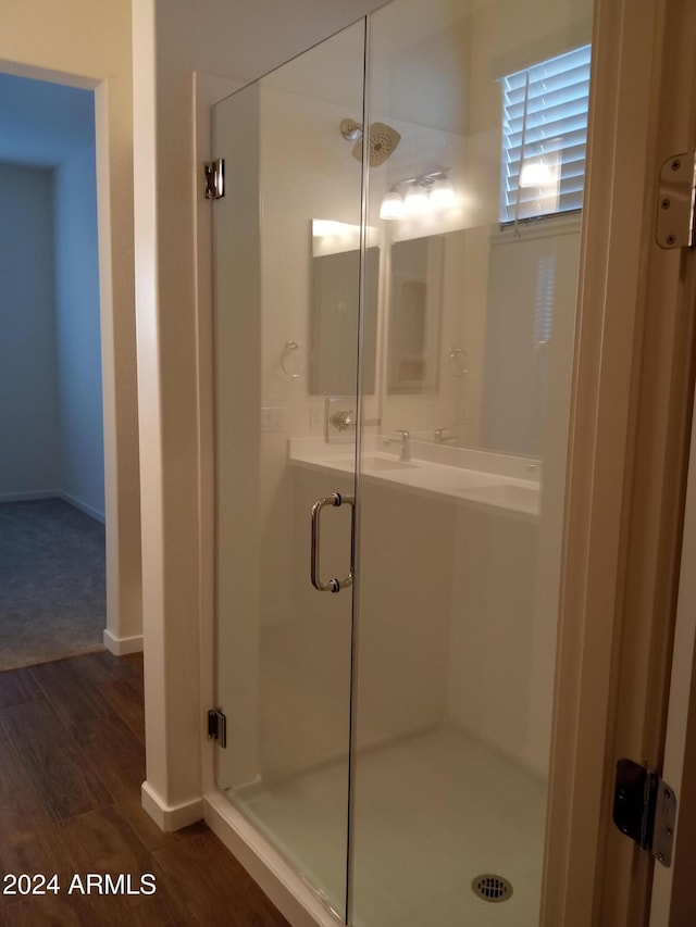 bathroom with wood-type flooring and a shower with door