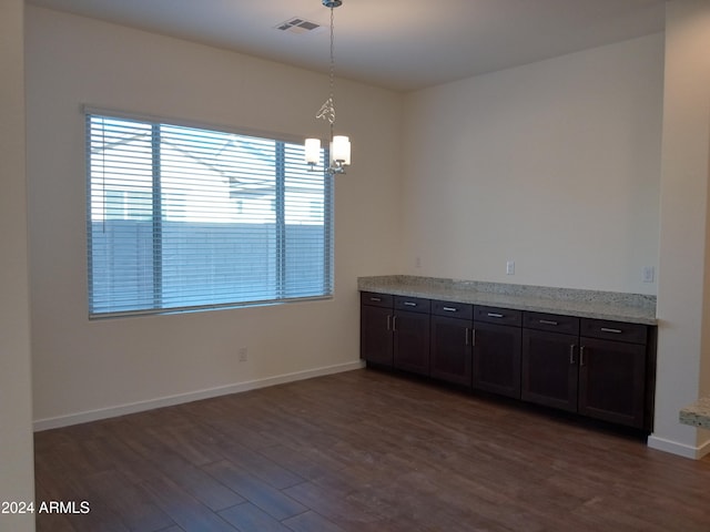 unfurnished dining area featuring dark wood-type flooring and a notable chandelier