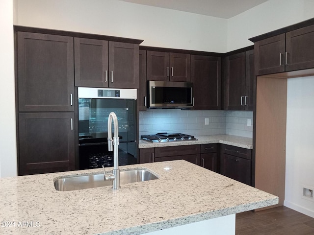 kitchen featuring light stone countertops, sink, dark hardwood / wood-style flooring, backsplash, and appliances with stainless steel finishes