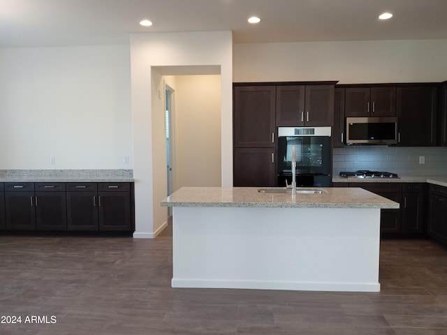 kitchen featuring appliances with stainless steel finishes, a center island with sink, light stone counters, and sink