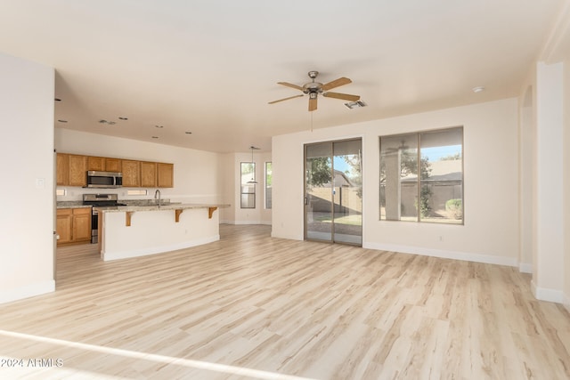 unfurnished living room featuring light hardwood / wood-style floors, sink, and ceiling fan