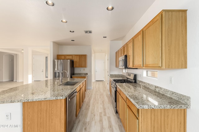 kitchen with a center island with sink, light hardwood / wood-style floors, sink, and stainless steel appliances